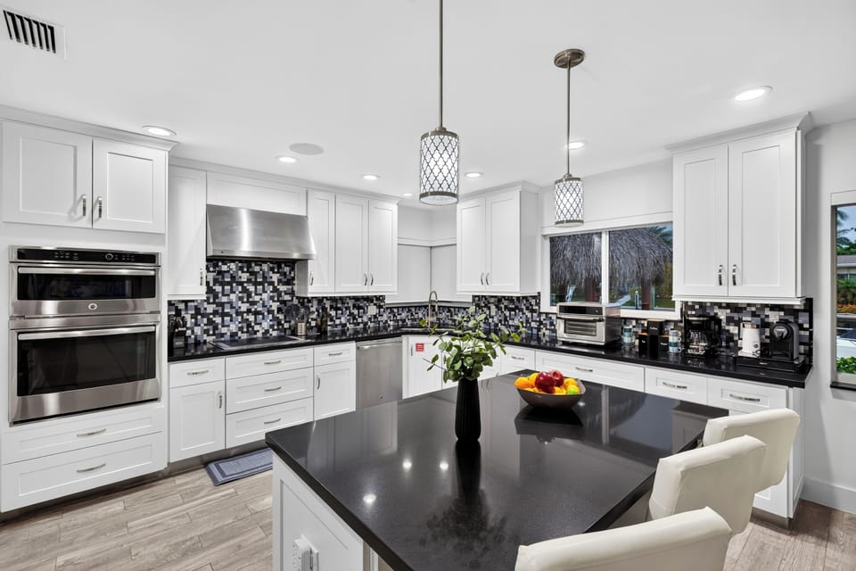 Modern kitchen with sleek black countertops, white cabinetry, stainless appliances, and island seating.