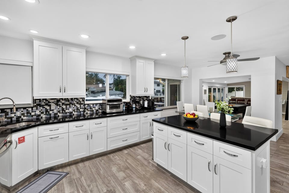 Modern kitchen with a large island, sleek black countertops, and open flow to the dining and living areas.