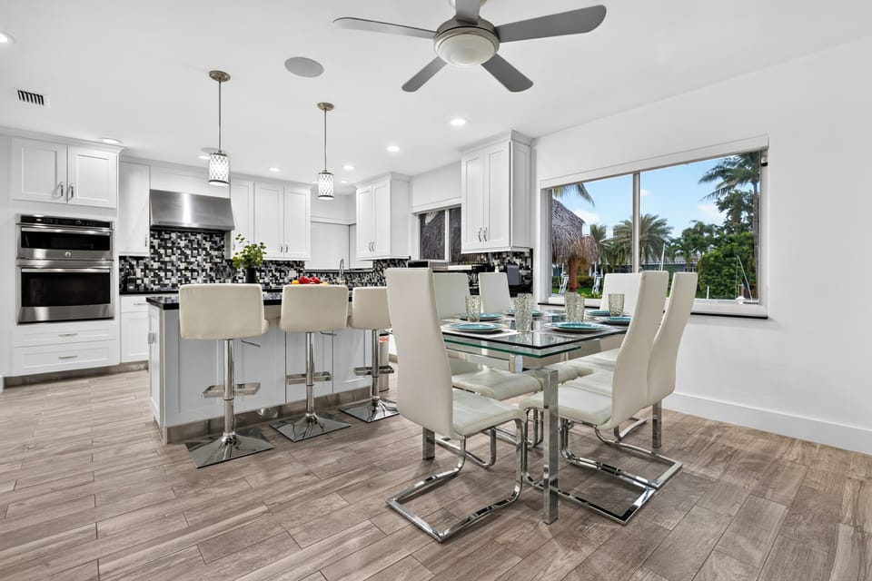 Bright kitchen and dining area with island seating, modern finishes, and tropical canal views.