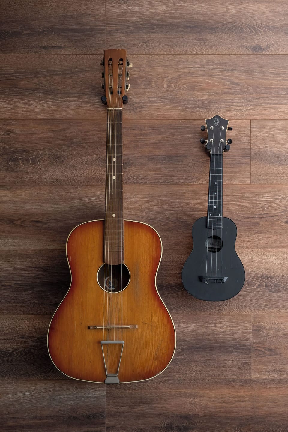 Two acoustic guitars hang symmetrically against a dark, rich wood-paneled wall. The musical instruments serve as a unique and creative decor element inside the apartment.
