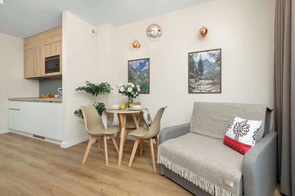Cozy living and dining area with a sofa, dining table, and kitchenette in an open-plan layout.