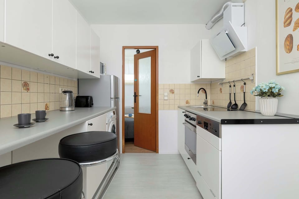 The kitchen features sleek cabinets, dark countertops, and bar seating beneath a bright window. The layout offers plenty of space for cooking.