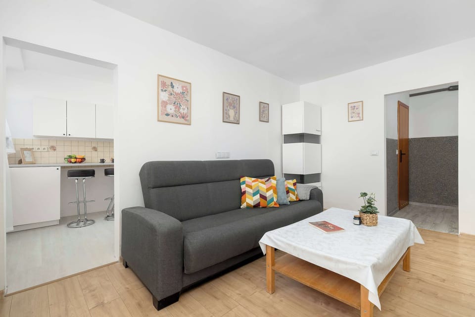 The sitting area is viewed toward the kitchen entrance, showcasing the apartment's practical and open layout. Simple décor keeps the room uncluttered.