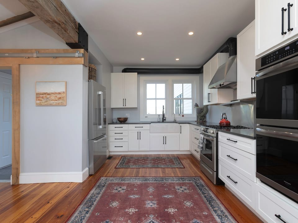 Your fully equipped kitchen invites creativity with sleek white cabinets, stainless steel appliances, and warm hardwood floors—perfect for whipping up meals or gathering over morning coffee.