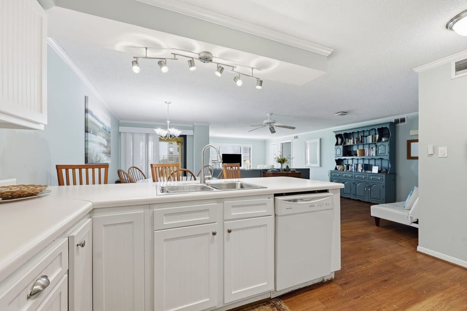 Picture yourself cooking in this bright, open kitchen with crisp white cabinetry, modern appliances, and flowing hardwood floors connecting to your dining and living spaces.