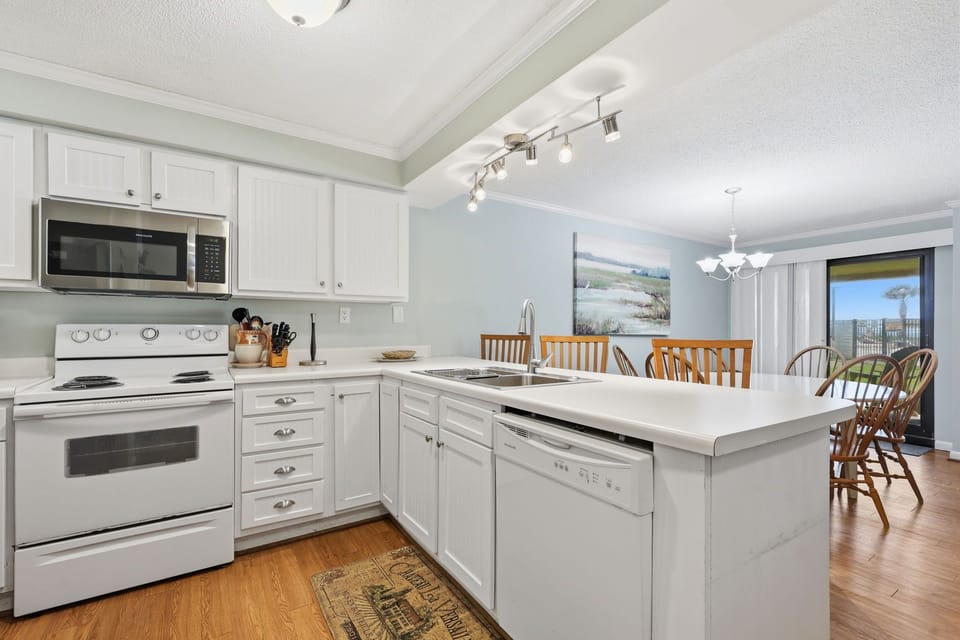 Your fully equipped kitchen opens to a sunlit dining space where meals and memories come together. Bright counters, modern appliances, and a welcoming island invite you to cook and gather with ease.