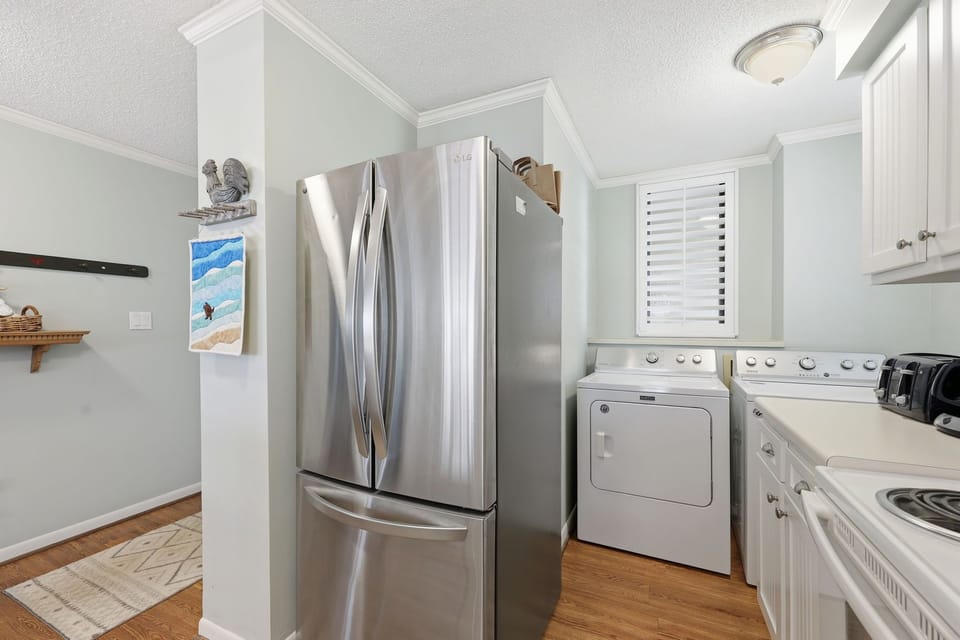 Bright and convenient kitchen corner featuring sleek stainless-steel fridge, in-unit washer and dryer, and modern stove—everything you need for a comfortable stay.