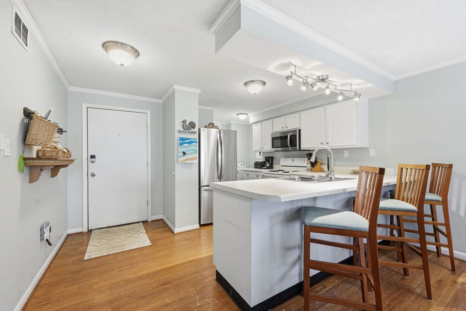Your bright, open-concept kitchen invites you to gather around the breakfast bar, where coastal charm meets modern convenience for meals and memories.