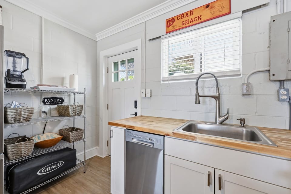Your kitchen offers warm butcher block countertops, a farmhouse-style sink, and all the essentials for preparing meals in coastal comfort beneath playful "Crab Shack" charm.