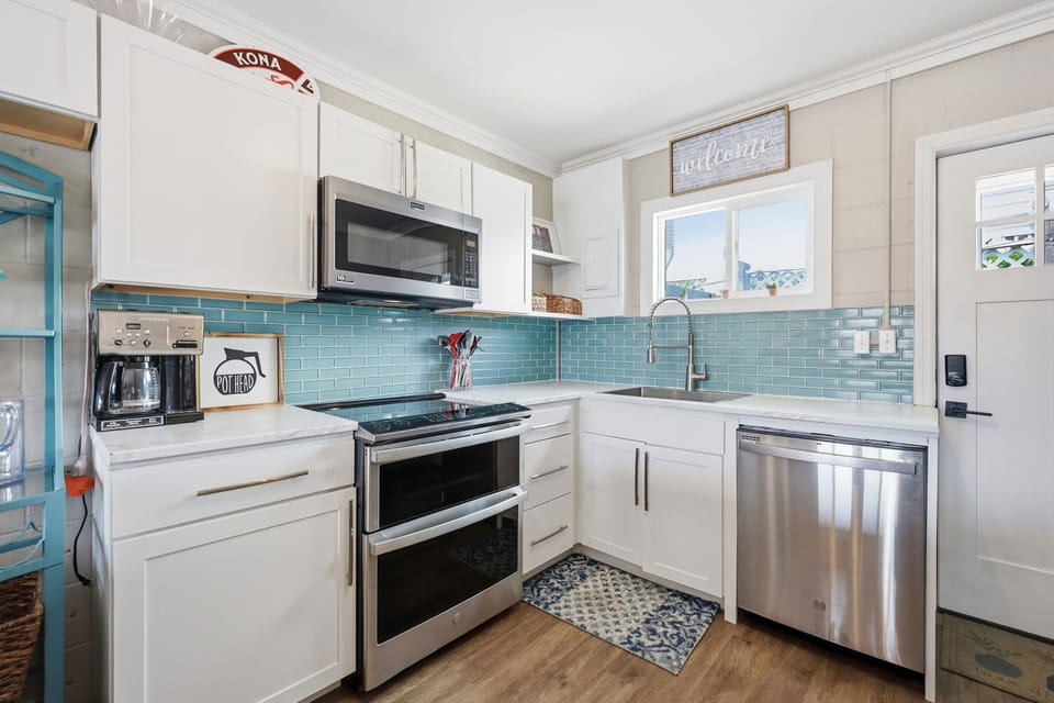 Your bright, fully-equipped kitchen features modern appliances, gleaming countertops, and a cheerful turquoise backsplash to inspire your morning coffee routine.