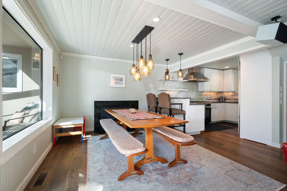A solid wood table set under pendant lights for shared meals and lively conversation.