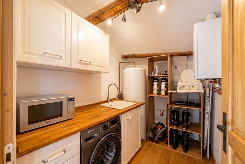 A practical utility room with washer, microwave and handy ski boot storage.