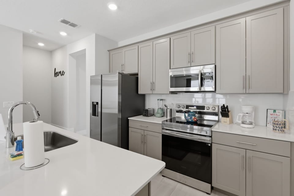 Modern kitchen with quartz countertops, stainless steel appliances, and seating for four at the island.
