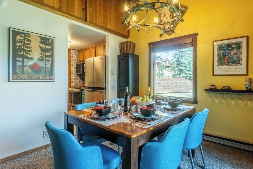 Gather around this inviting dining table, where mountain views through the window complement your meals. The warm wood accents and rustic chandelier create a cozy atmosphere perfect for sharing stories and savoring local flavors together.