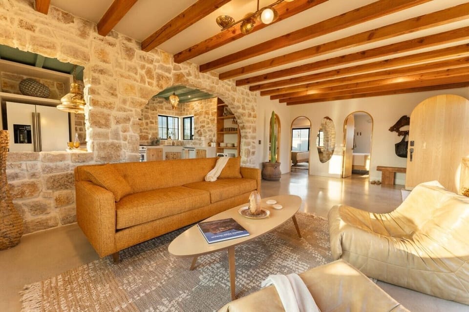 Exposed wood beams, handcrafted stonework, and an open-concept layout create a warm, inviting space that blends timeless character with modern comfort.