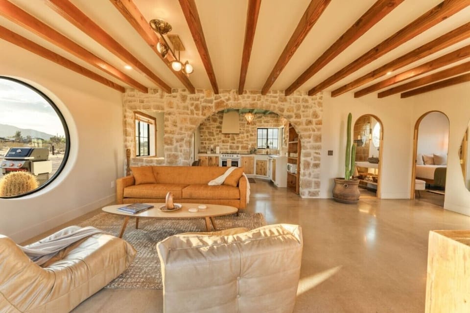 Gather in this beautifully designed open-concept space, where warm wood beams, natural stone accents, and the signature round window create an unforgettable desert retreat.