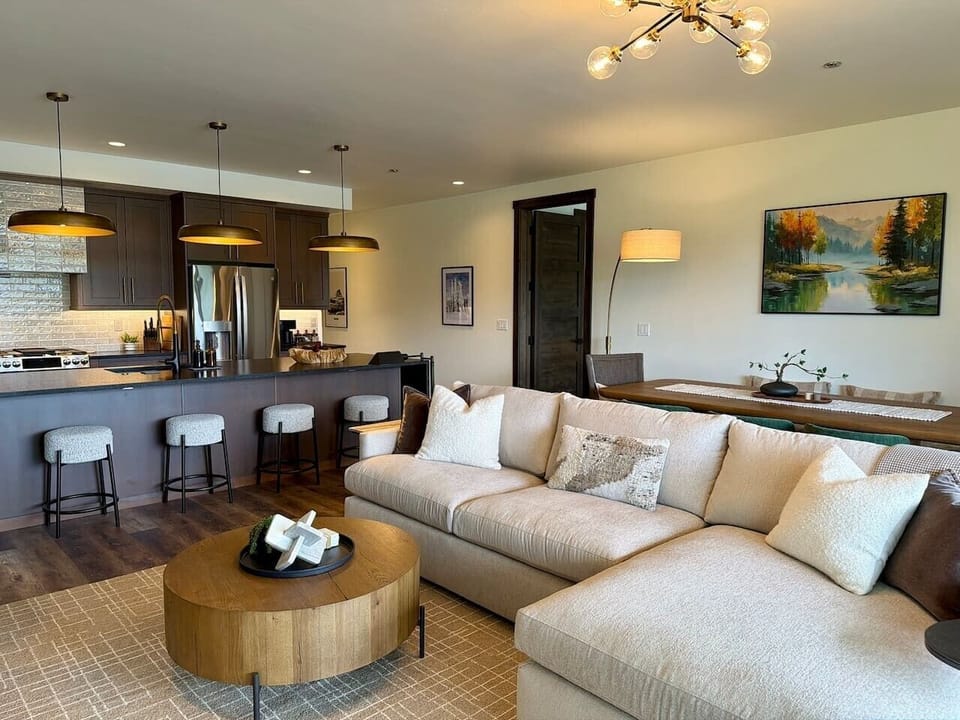 Snowghost Social offers an open living room with a plush sectional, kitchen views, warm lighting, and plenty of space to gather.