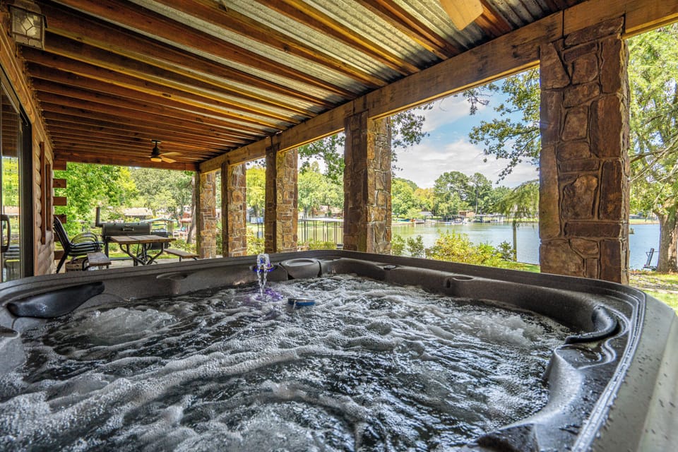 Private lakeside hot tub on a rustic covered patio with serene views