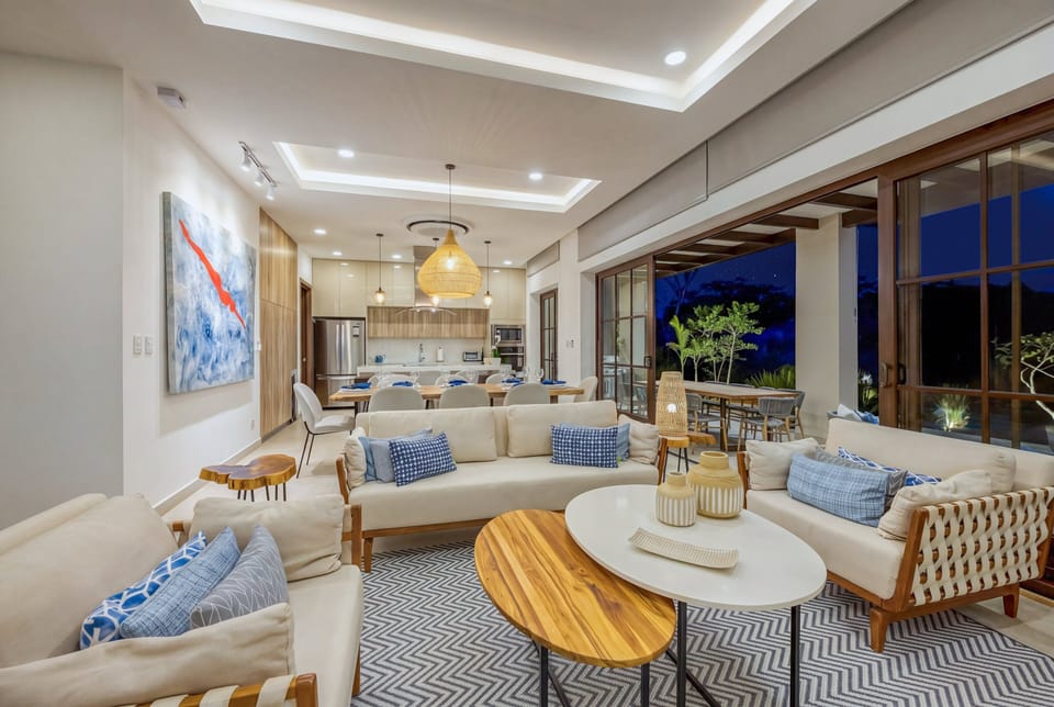 Bold artwork, teak accents, and a woven pendant light anchor this elegant living space at night. The open sliders keep the breeze flowing through.
