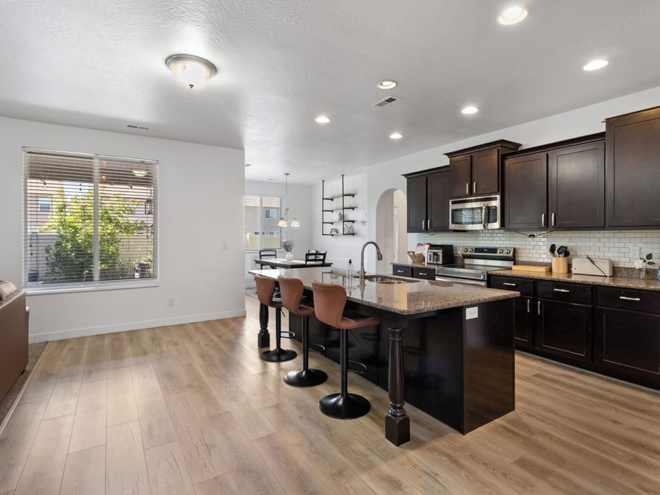 Sleek dark cabinetry, stainless steel appliances, and a functional island bar with seating for three. Built for cooking together.
