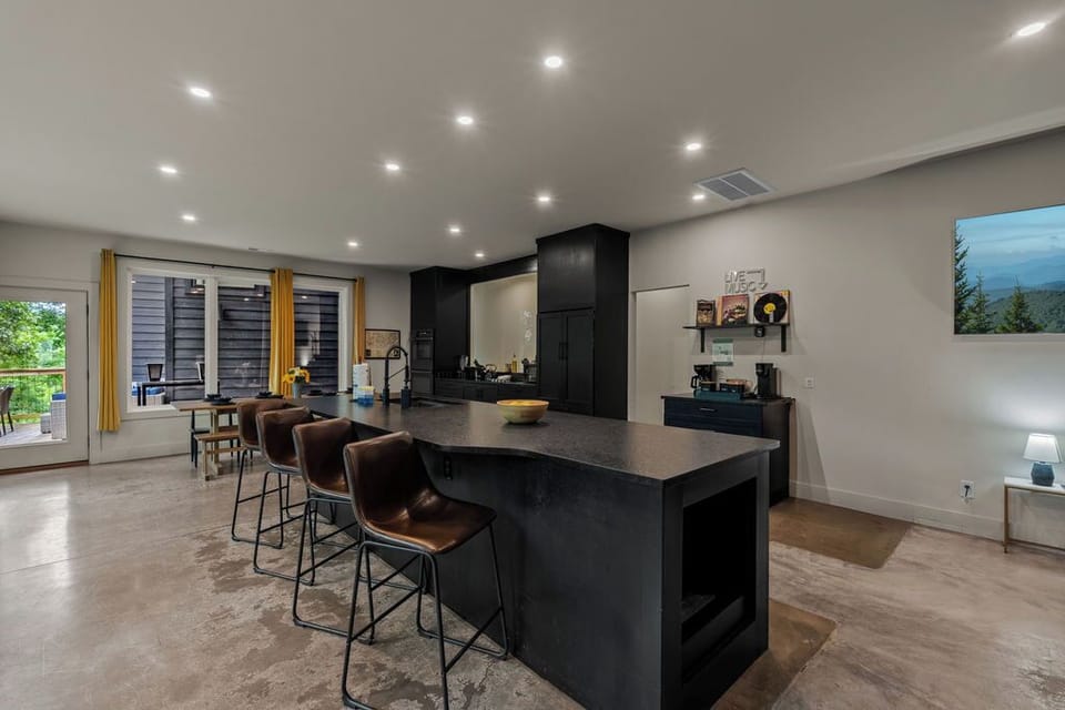 Sleek kitchen island with bar stools, open layout, and easy access to the dining area and wooded deck.
