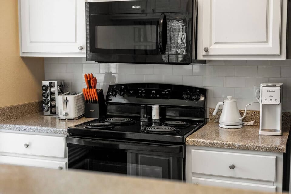 Well-equipped kitchen with a full-size stove, oven, microwave, kettle, coffee maker, and countertop essentials for preparing meals and drinks during your stay.