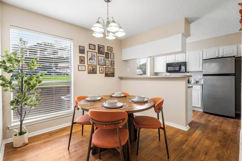 Dining area with seating for six, warm wood flooring, modern lighting, and an open pass-through to the kitchen, creating a comfortable setting for shared meals and conversation.