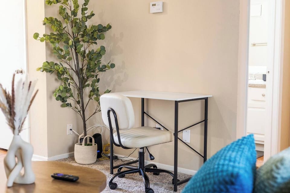 Dedicated workspace with a desk, comfortable chair, nearby power access, and simple greenery, providing a practical spot for remote work or planning the day.