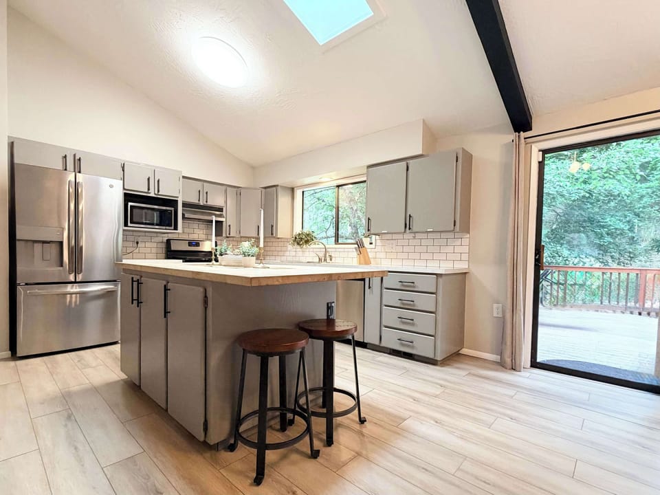 Bright kitchen with skylight, butcher-block island, stainless appliances, and sliding door to the back deck — indoor-outdoor flow built in