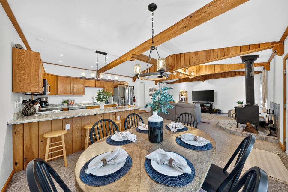 A close-up of the formal dining table, perfectly positioned under a rustic chandelier and convenient to the breakfast bar.