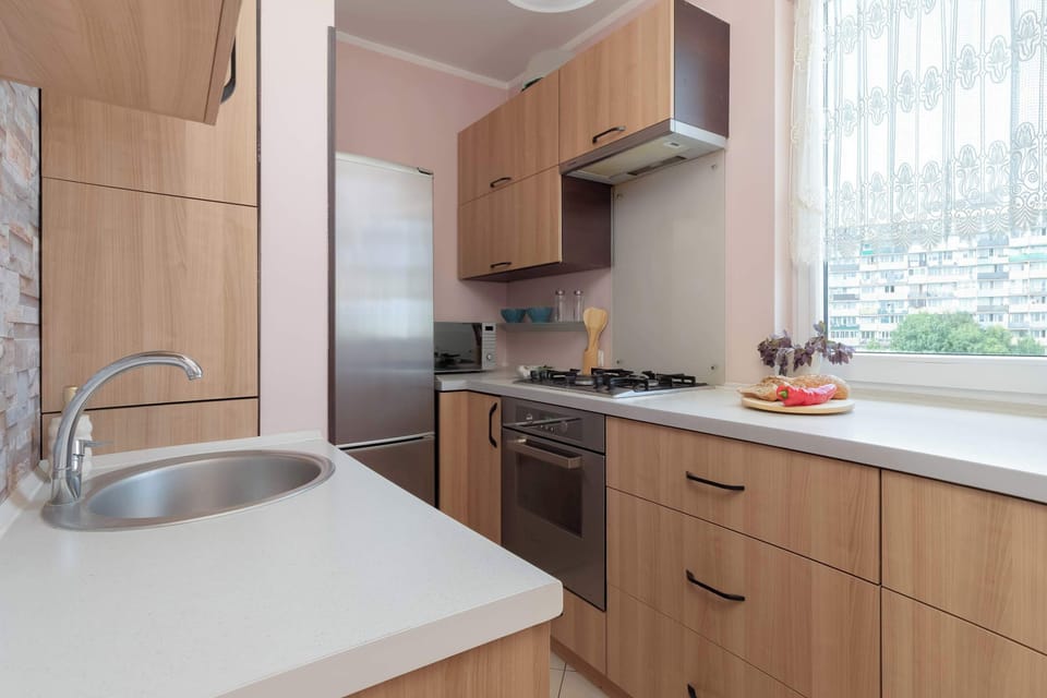 A bright kitchen with wooden cabinets and a window above the countertop. The space is fully equipped for preparing meals.
