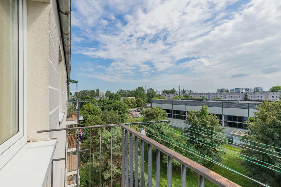 A balcony with views of the surrounding greenery and nearby buildings. It offers a pleasant spot to enjoy the fresh air.