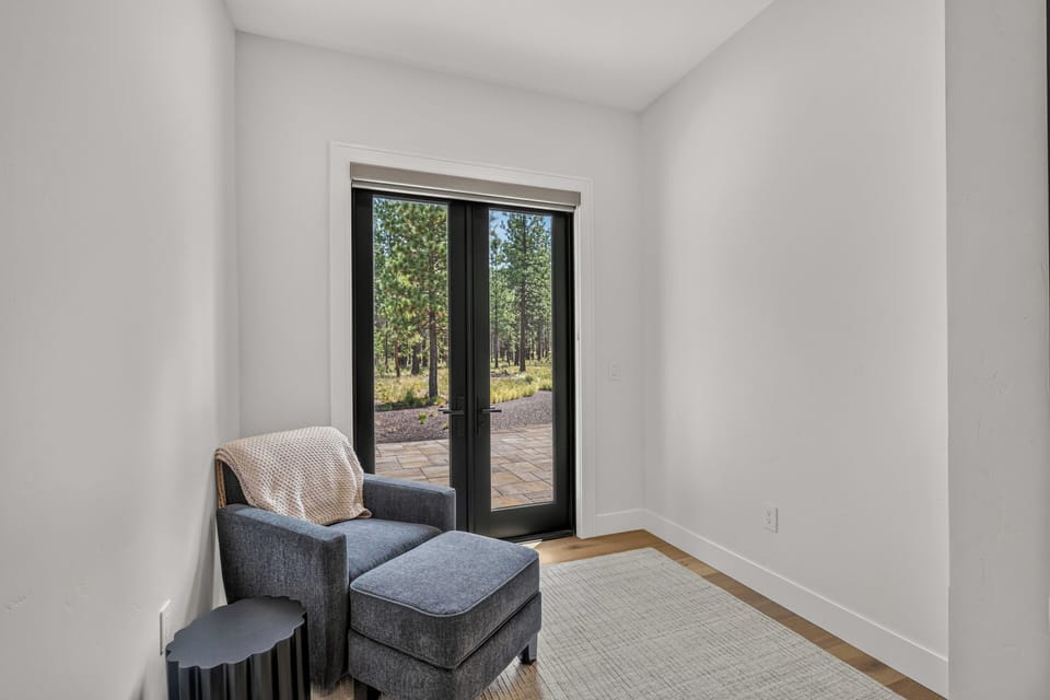 Curl up with a book in this tranquil nook, where sunlight filters through tall pines beyond your private terrace door, creating a perfect retreat.