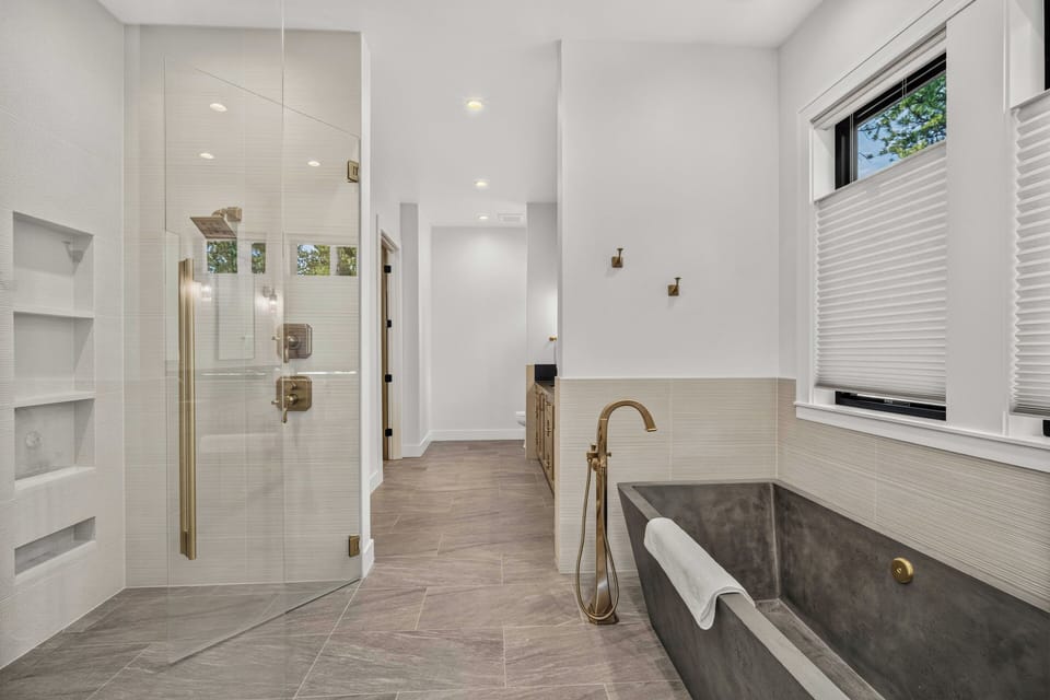 Unwind in your luxurious spa-inspired bathroom, featuring a sleek soaking tub, spacious glass-enclosed shower, and elegant finishes that create your personal retreat.