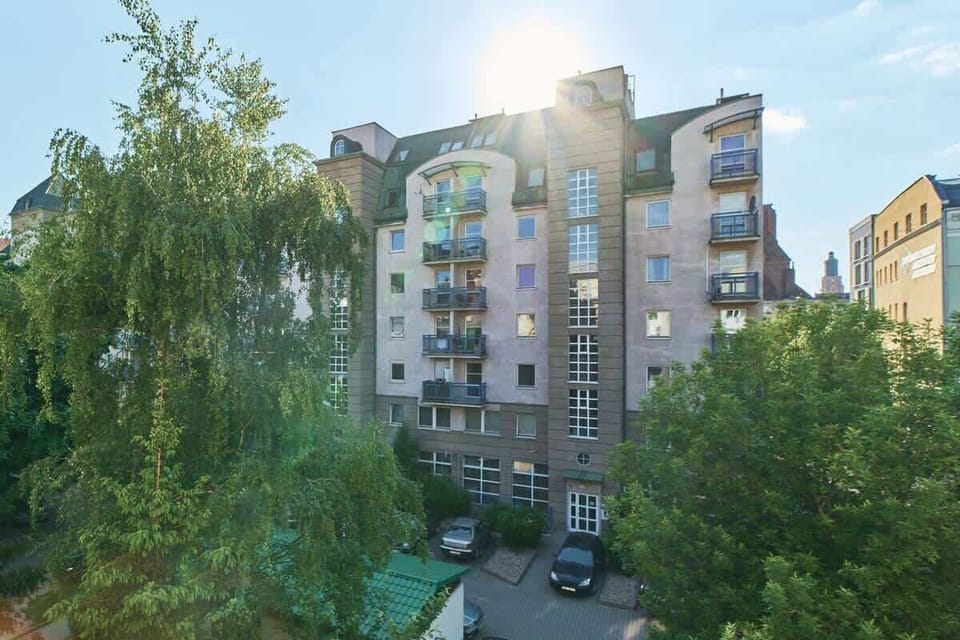 A picturesque view of nearby buildings surrounded by green trees and open space.