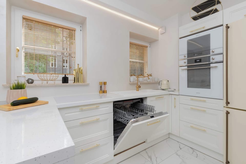 Another perspective of the kitchen highlights the glossy cabinets, built-in appliances, and generous countertop space. The layout is designed for convenient meal preparation.