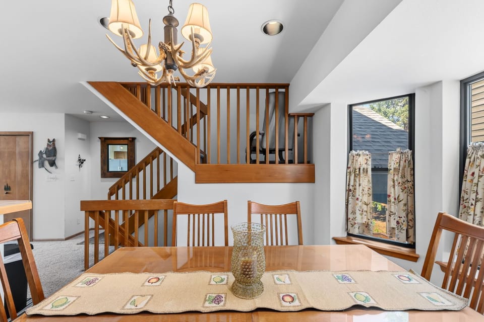 Gather around this inviting dining table with warm wood tones and vaulted ceilings that create an open, airy atmosphere perfect for memorable meals together.