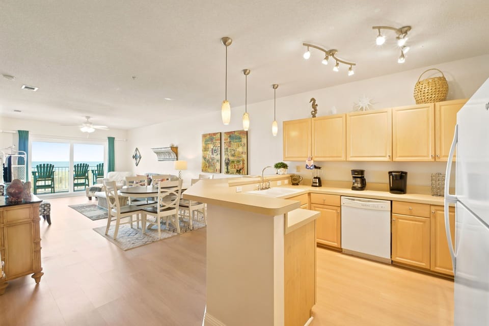 Step into your bright, open living space with a fully equipped kitchen, cozy dining nook, and inviting ocean views through expansive balcony doors. Every detail is ready for your relaxing getaway.