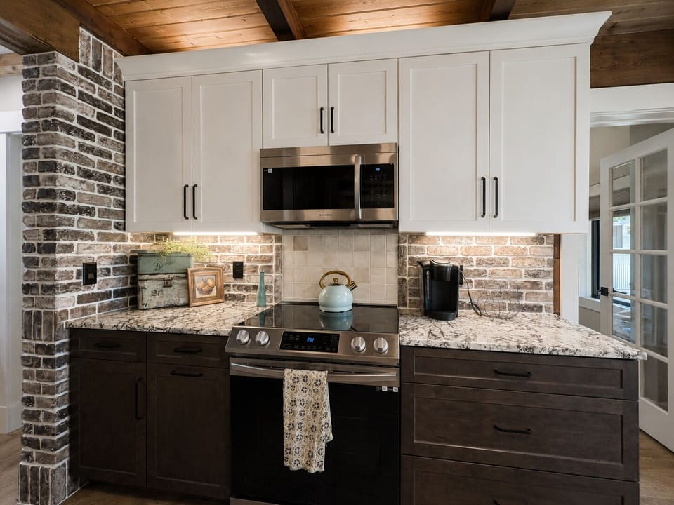 Your fully equipped kitchen blends rustic charm with modern convenience, featuring granite countertops, a gas range, and exposed brick backsplash—ready for cozy mornings and home-cooked meals.