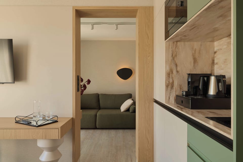 Salon został urządzony w nowoczesnym stylu, łączącym naturalne drewno, jasne beże i oliwkową zieleń. Znajduje się w nim wygodna, rozkładana sofa. Z pomieszczenia można wyjść bezpośrednio na balkon.
