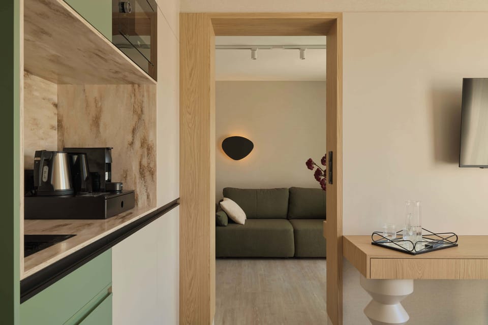 Salon został urządzony w nowoczesnym stylu, łączącym naturalne drewno, jasne beże i oliwkową zieleń. Znajduje się w nim wygodna, rozkładana sofa. Z pomieszczenia można wyjść bezpośrednio na balkon.