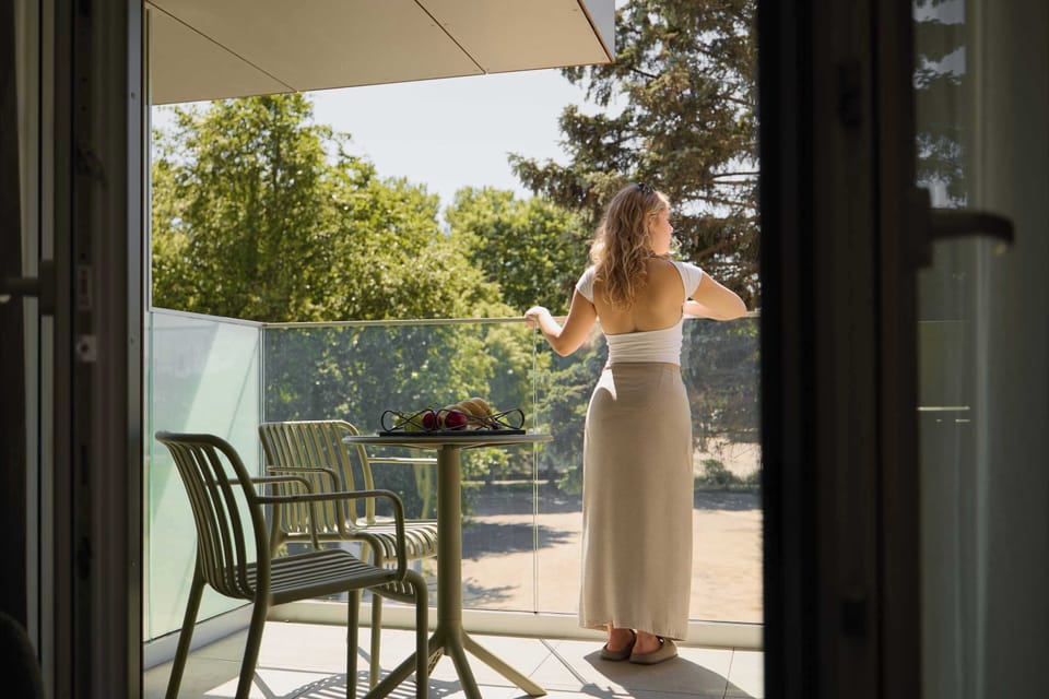 Balkon wyposażony jest w stolik i krzesła. Rozciąga się z niego widok na otaczającą zieleń. Jest to idealne miejsce na łyk porannej kawy lub odpoczynek na świeżym powietrzu.