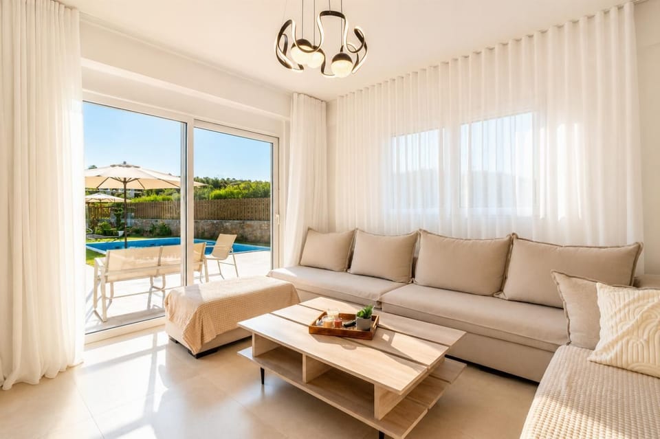 Bright living room with soft neutral decor, elegant curtains, and direct access to the private pool terrace.