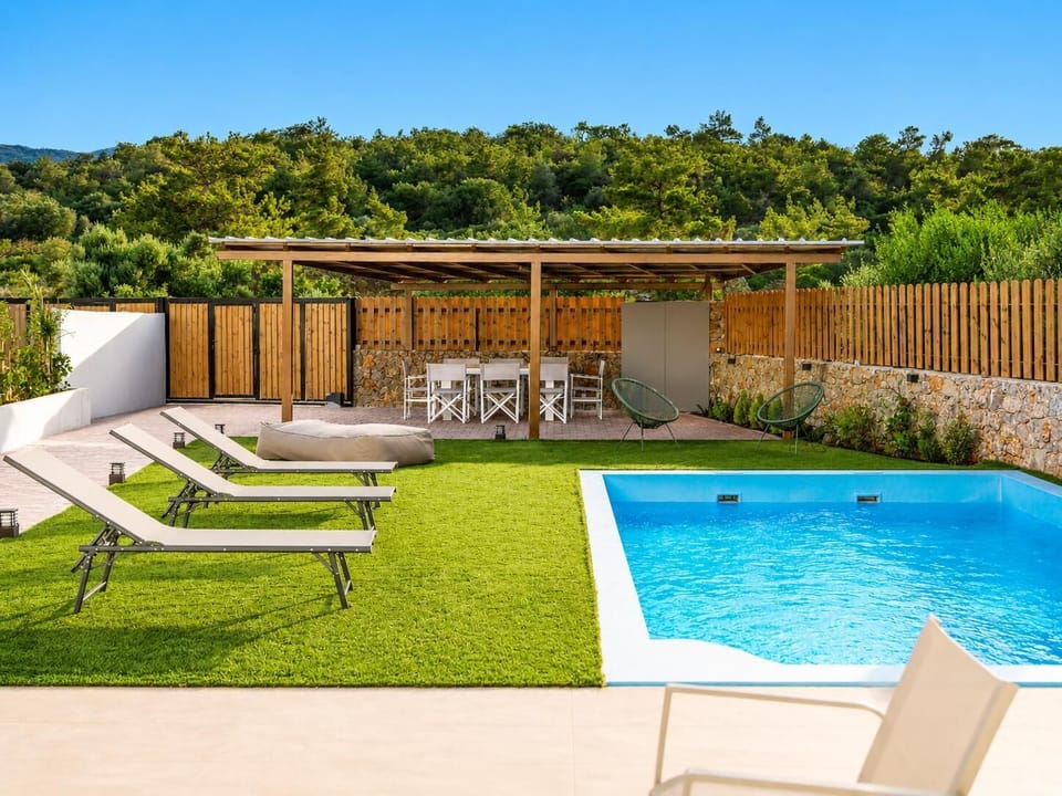 Sunny private pool area with sun loungers, shaded outdoor dining, and peaceful forest surroundings.