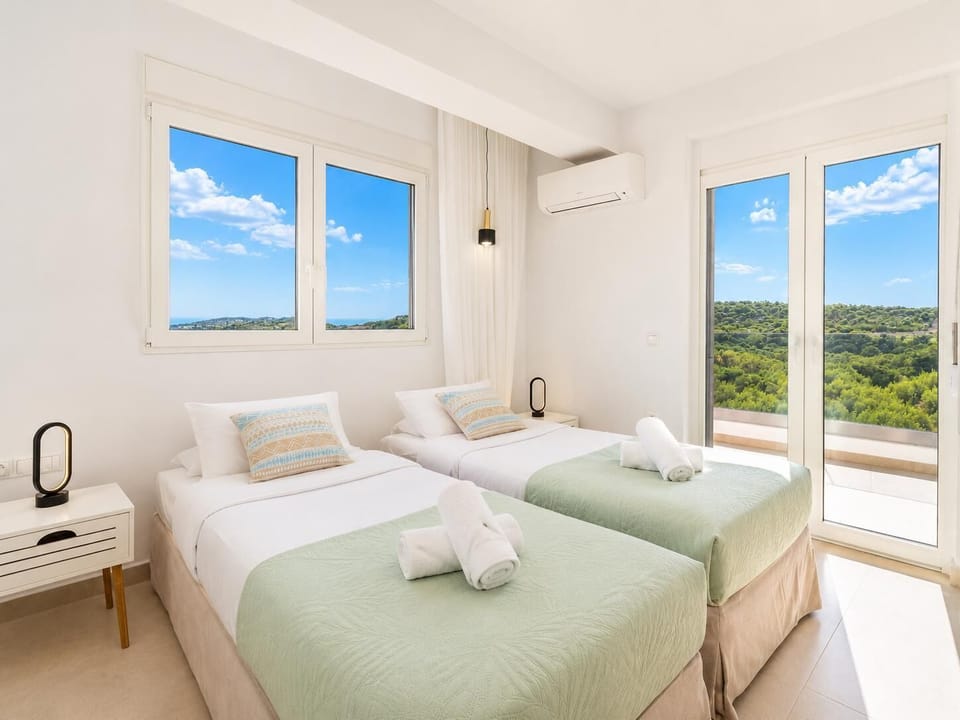 Bright twin bedroom with soft green accents, balcony access, and beautiful countryside views.