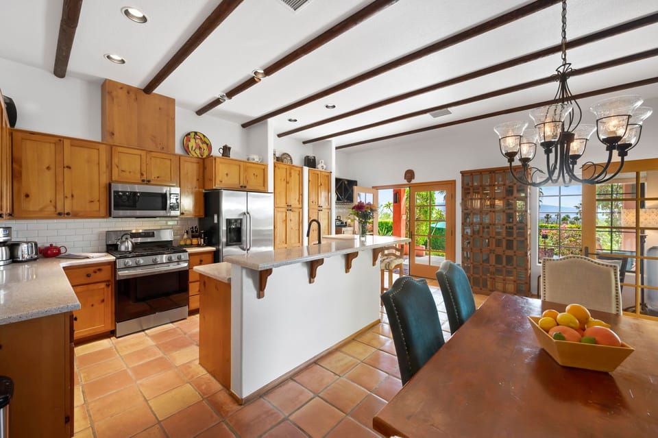 Your spacious kitchen and dining area boasts warm wood cabinetry, exposed beam ceilings, and stainless steel appliances—ideal for preparing meals together and gathering around the beautiful wooden table.