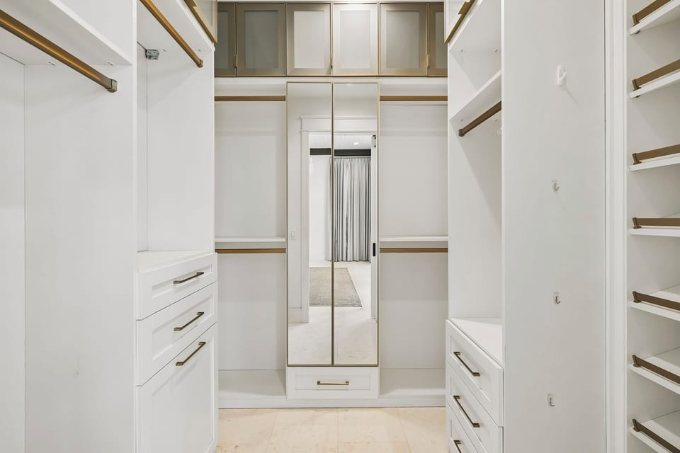 Your stylish walk-in closet features bright white built-ins, elegant wood accents, and a full-length mirror—perfect for organizing and getting ready each day.