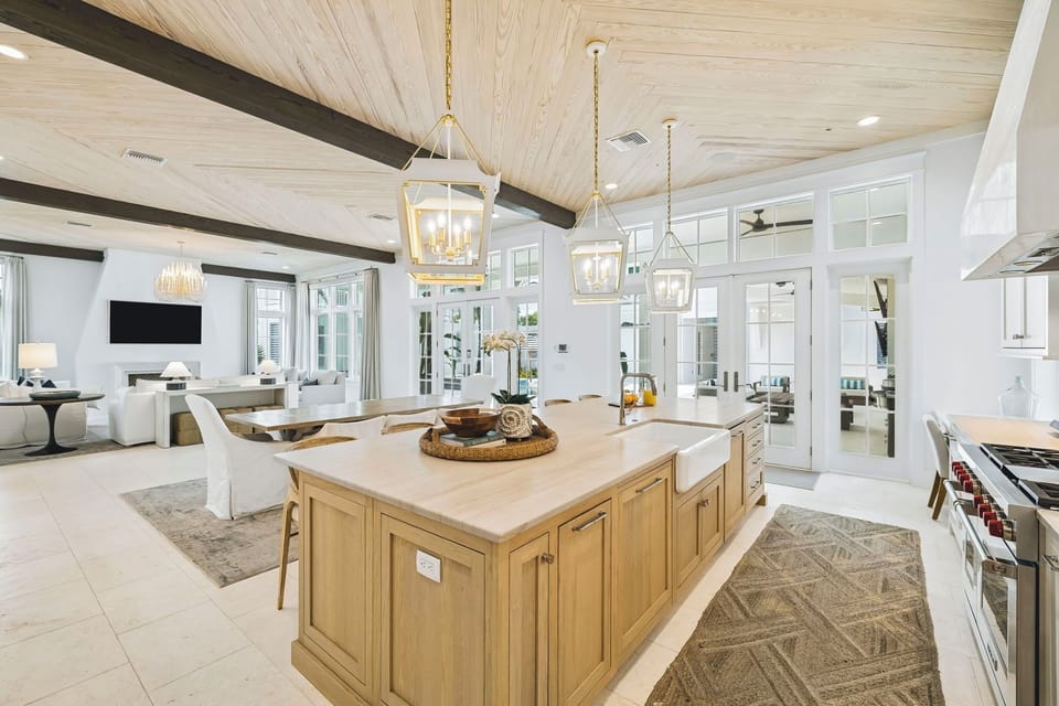Picture yourself preparing meals in this airy, coastal-chic kitchen with soaring wood-beamed ceilings, spacious marble island, and a seamless flow into your bright living spaces.