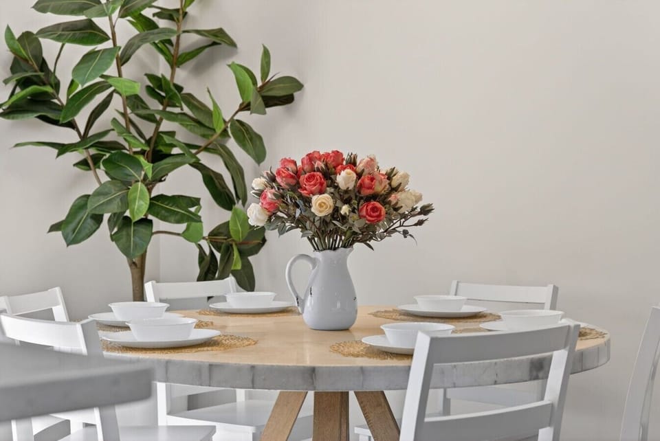 Dining Area | Round Wood Table | Floral Centerpiece & Woven Placemats