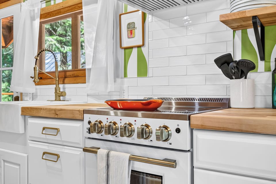 Bright designer kitchen with farmhouse sink, brass accents, and chef-style range